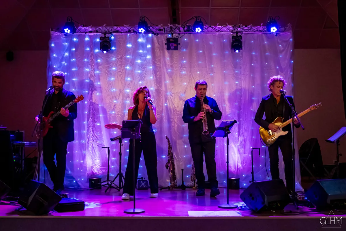 Le groupe Malaca sur scène : chanteuse, guitares, basse et saxophone sous les lumières